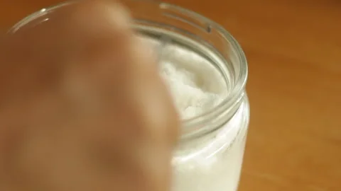 A teaspoon of table sea salt is being scooped with measuring spoon Stock Footage 221813803