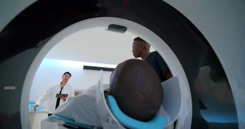 Tech is adjusting head coil as clinician is explaining procedure and preparing Stock Footage 341937731