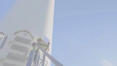 Tech checking power on laptop while camera tilting upward, live data rising wind Stock Footage 332902049