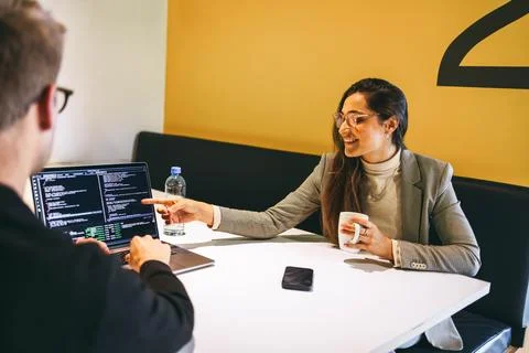 Tech colleagues discussing software design and coding in a coworking office Stockfoto's