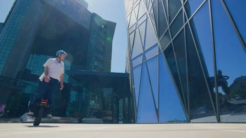 Tech commuter balances on one-wheel in front of office Stock Footage 308658551