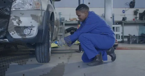 Tech crouching at SUV wheel turning wrench loosening lugs for service globe Stock Footage 329904371