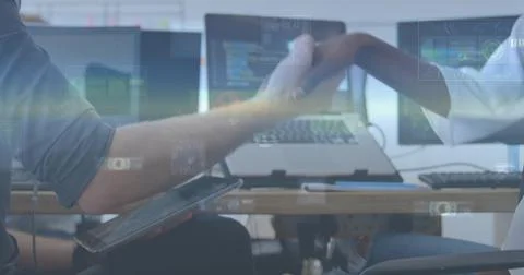 Tech devs reaching across desk shaking hands over code screens overlay covering 写真素材