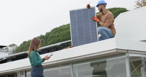 Tech kneeling on roof after tablet test aligning panel with gloves  and  tool; Stock Footage 337886381