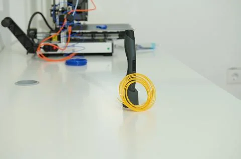 Tech Lab Scene With Yellow Coiled Cable and Handheld Device on White Workbenc Stock Photos