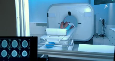 Tech positioning patient and starting table sliding into scanner while doctor Stock Footage 340010944