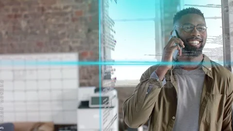 Tech pro speaking on smartphone in loft office, call starting activating cyan Stock Footage 333318120