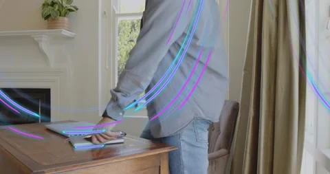 Tech pro stacking laptop on tablet tapping smartphone activating neon overlay Stock Footage 317733942