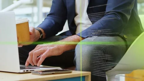 Tech pro typing laptop holding cup, keys activating green code overlays crossing Stock Footage 335739265
