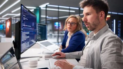 Tech Professionals Collaborating On Code In Contemporary Workspace Foto stock