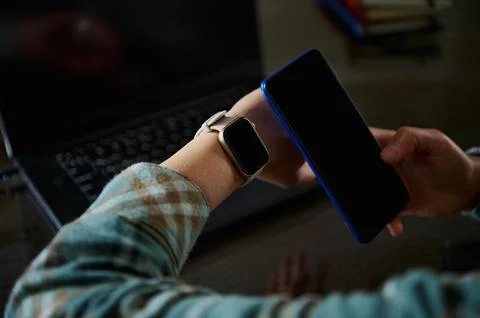 Tech-Savvy Individual Using Smartwatch and Smartphone in Modern Workspace Stock Photos