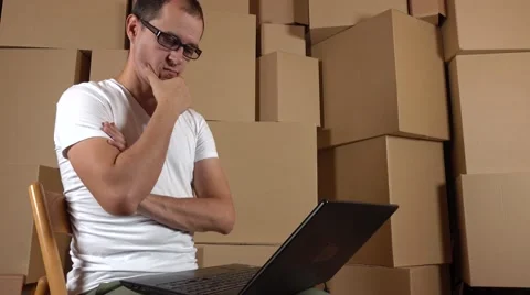 Tech of a small online store at work. Man in glasses thinking and typing on his Stock Footage 67648468