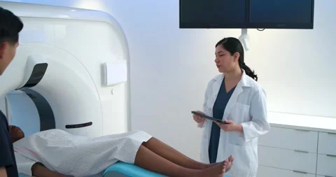 Tech is starting scan and sliding patient into CT gantry while team is checking Stock Footage 343838029