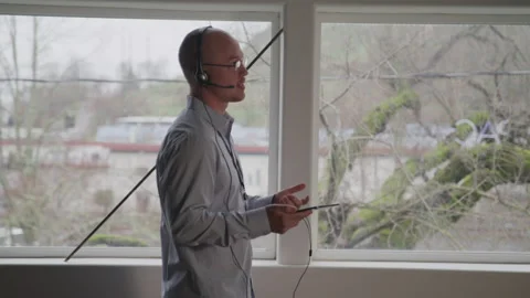 Tech Support Guy Talking on a Headset with a Tablet in His Office Stock Footage 208798057