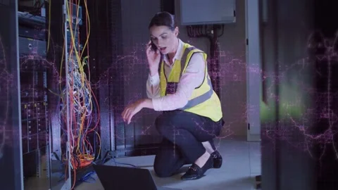 Tech tapping PC and calling, fixing cables in data center while purple wave Stock Footage 332591961