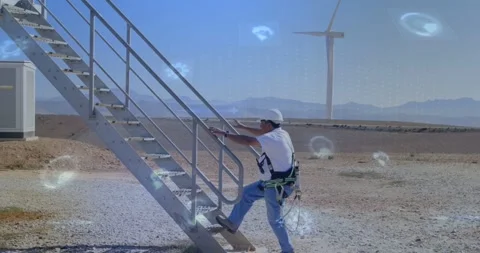Tech walking to metal stairs on wind farm, placing hand on rail, climbing while Stock Footage 334312634