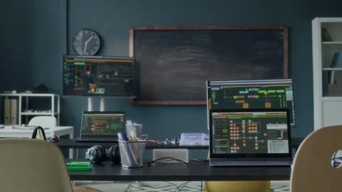 Tech Workspace with Multiple Laptops Running Software in Front of Blackboard Stock Footage 284424971