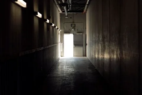 Technical corridor with light at the end. exit sign above the door Foto stock