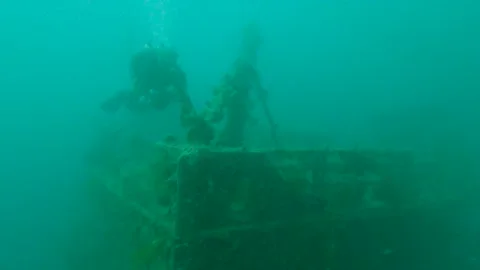 Technical diver Swimming along bow of large underwater shipwreck Stock Footage 229875273