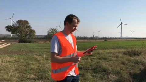 Technical engineer looking at tablet and wind turbines Stock Footage 98154833