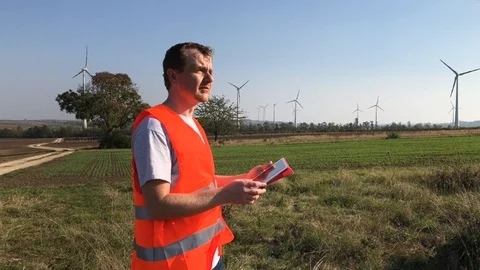 Technical engineer noting in tablet looking at wind turbines Stock Footage 98188062