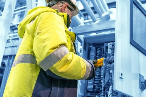 An technical engineer performs a measurement in a control cabinet Stock Photos