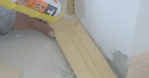 Technical man hands putting glue to brown baseboard Stock Footage 136450132