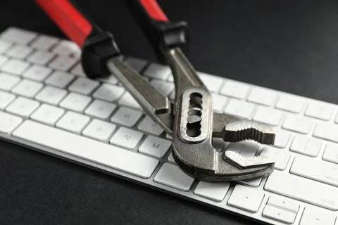 Technical support concept. Plumbing pliers and keyboard on black background.. 写真素材
