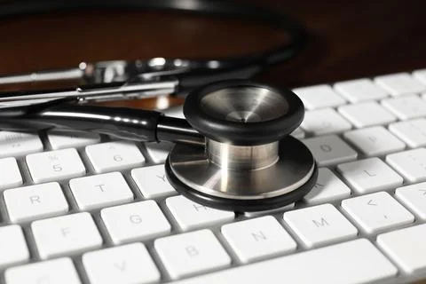 Technical support concept. Stethoscope and keyboard on wooden table, closeup Stock-Fotos