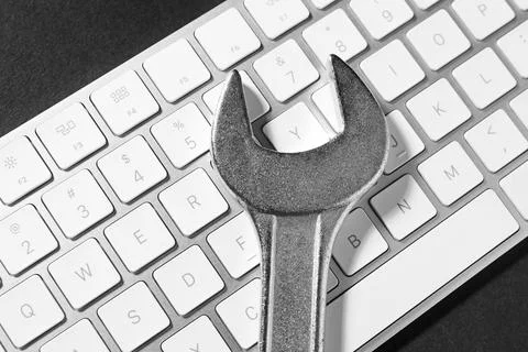 Technical support concept. Wrench and keyboard on black background, top view 写真素材