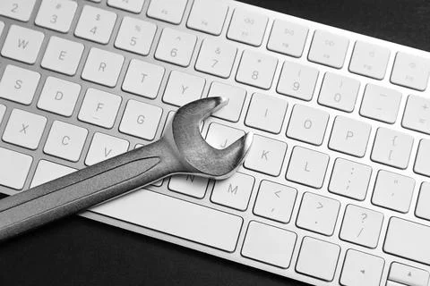 Technical support concept. Wrench and keyboard on black background, top view Stock-Fotos