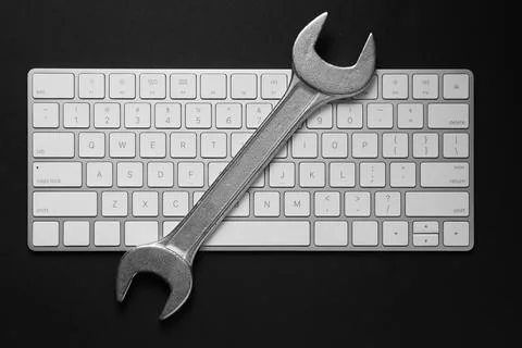 Technical support concept. Wrench and keyboard on black background, top view Stock-Fotos