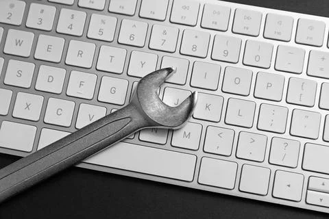 Technical support concept. Wrench and keyboard on black background, top view 写真素材