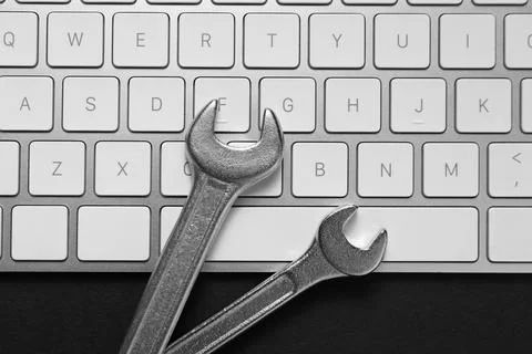 Technical support concept. Wrenches and keyboard on black background, top vie Stock-Fotos
