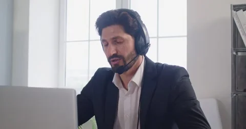 Technical support operator using headset and laptop, working in call centre 스톡 동영상 334698790
