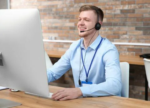 Technical support operator working with headset and computer at table in offi Stock Photos