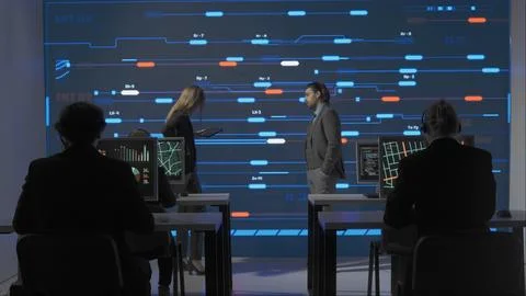 Technical support team in control room. Man and woman specialists discussing Stock Photos
