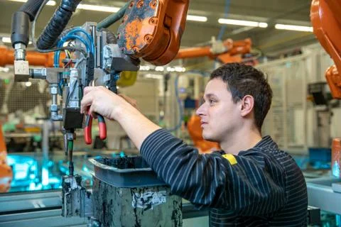 Technical worker performs maintenance robotic arms on the production line Stock-Fotos