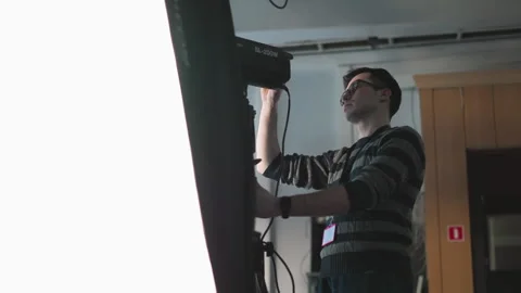 Technician adjusting power and settings on SL-200W light in studio setup Stock Footage 317541000