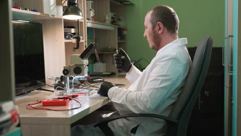 Technician Adjusting Screw Under Lamp with Electronic Components on Desk Stock Footage 283121255