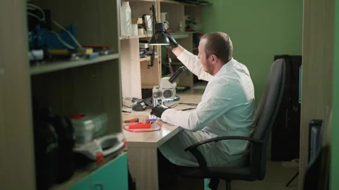 Technician Adjusts Lamp and Tests Circuit Under Microscope in Lab Stock Footage 283119884