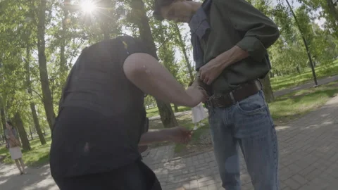 Technician adjusts microphone on actor in park before scene Stock Footage 308933307