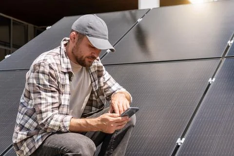 A technician analyzes the performance of a solar panel remotely using his sma Stock Photos