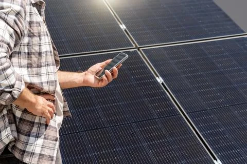 A technician analyzes the performance of a solar panel remotely using his sma Stock Photos