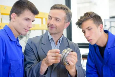 Technician and apprentices working with a machine Stock Photos