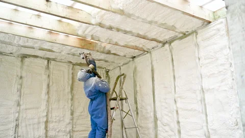 Technician applies polyurethane foam insulation to unfinished timber wall Stock Footage 346708591