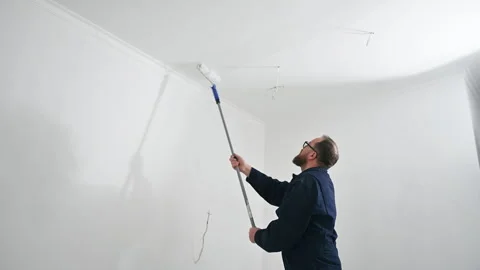 Technician applies white coating to ceiling in residential room. Painter uses Stock Footage 346708616