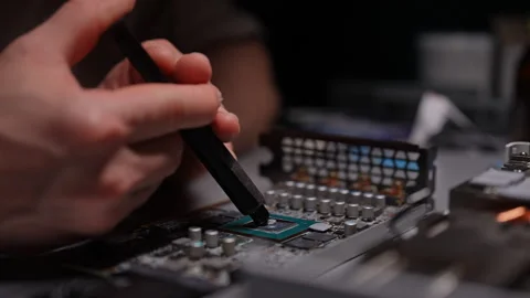 Technician applying thermal paste to GPU chip for improved circuit board cooling Stock Footage 290919890