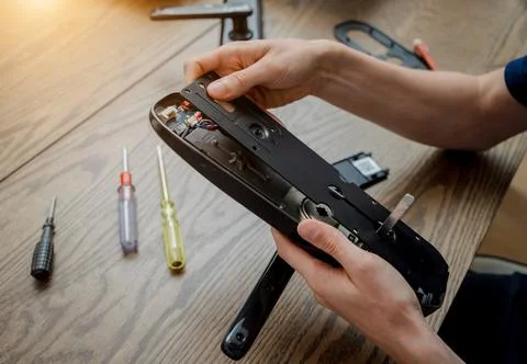 A technician assembles and installs smart electronic door lock for house Stock Photos