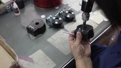 Technician assembling multiple black telescope focuser mounts using electric Stock Footage 334964472